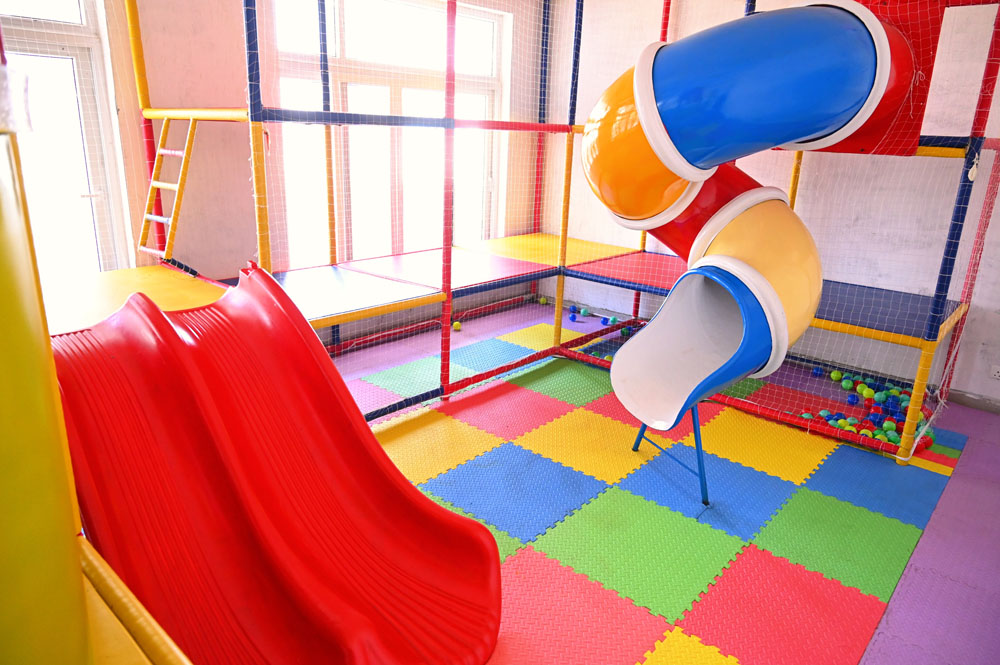 picture of indoor slide with blue yellow and zigzag slide from up to down. indoor play area for kids installed inside a home