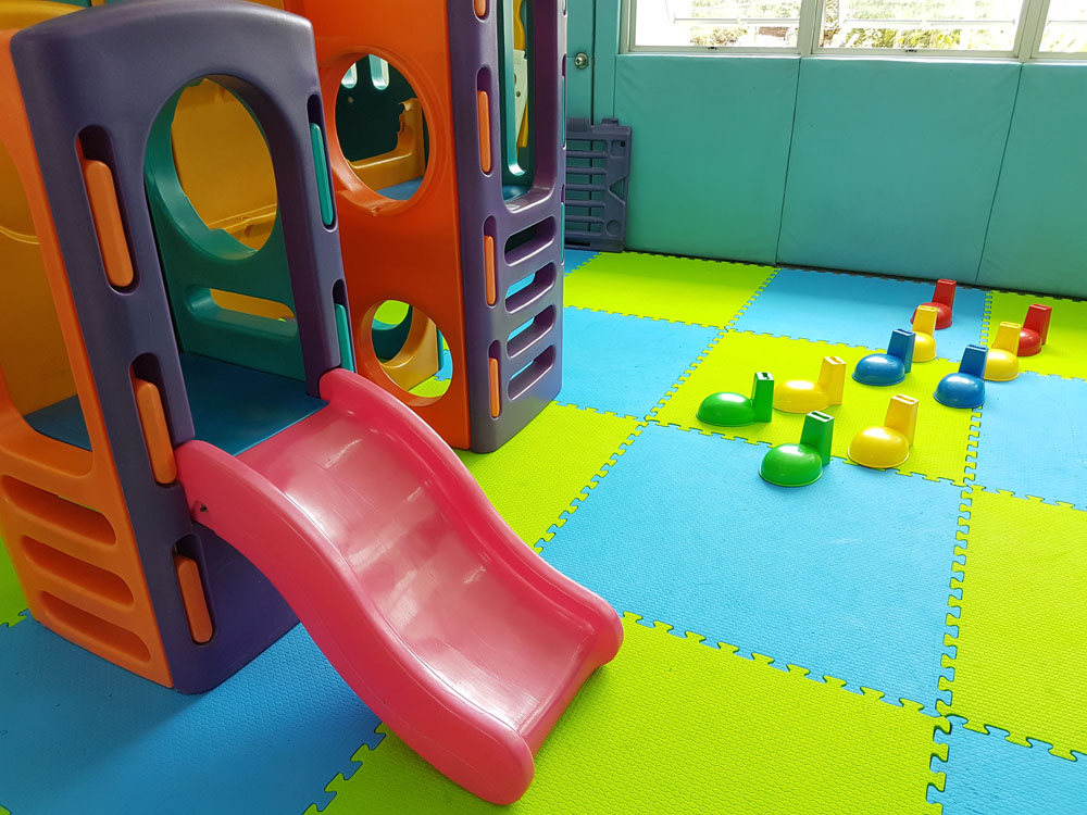 Children playground on activities area in Small room. Children run, slide on modern playground.